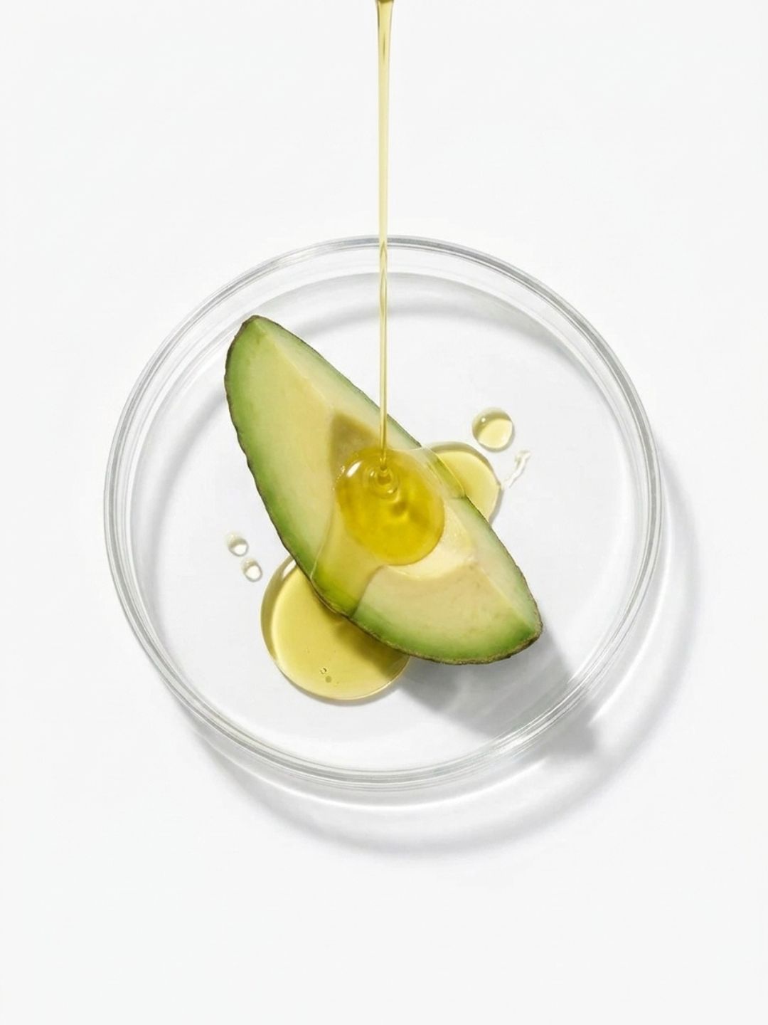Avocado oil being poured over a slice of avocado in a glass dish, a rich conditioning ingredient in LipQ Liquorice Balm
