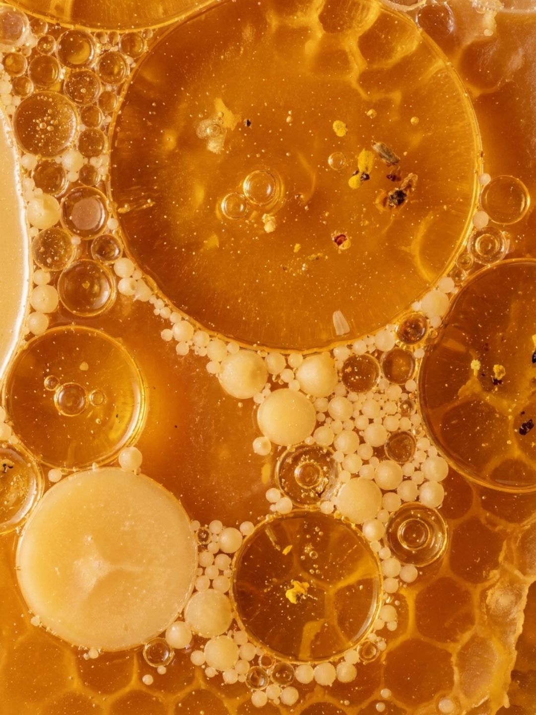 Close-up of golden beeswax and oils with droplets and bubbles, the natural protective wax that seals in moisture in LipQ Liquorice Balm