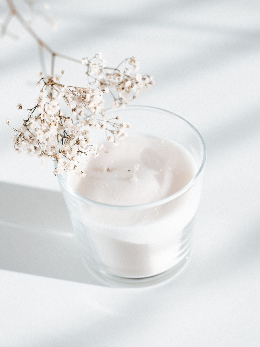A glass of milk with a sprig of small white flowers on the rim, representing the donkey milk in the salve