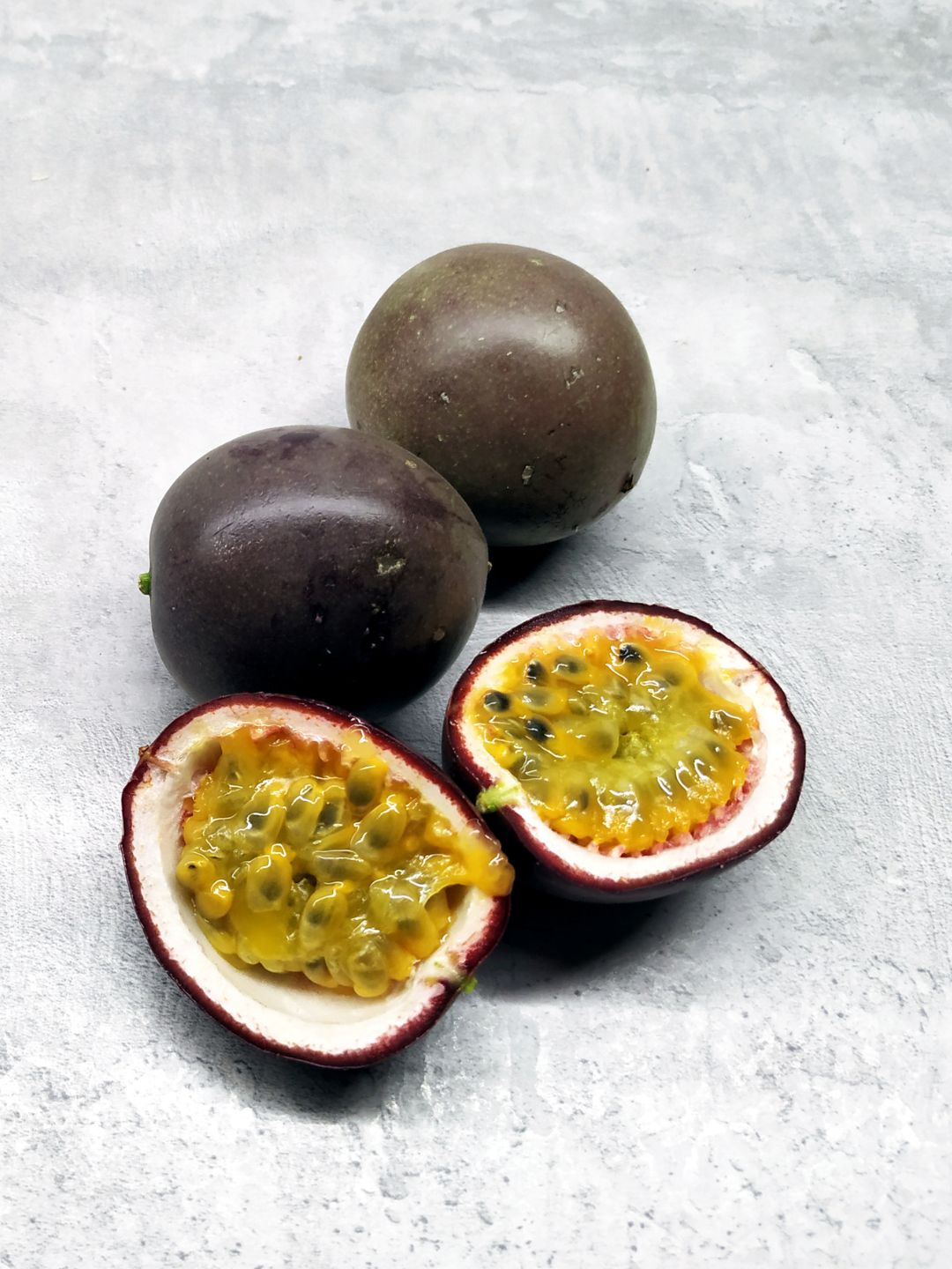 Two whole passion fruits and one cut in half to show its golden seeds and pulp, the passion fruit behind Hydrosil's seed complex