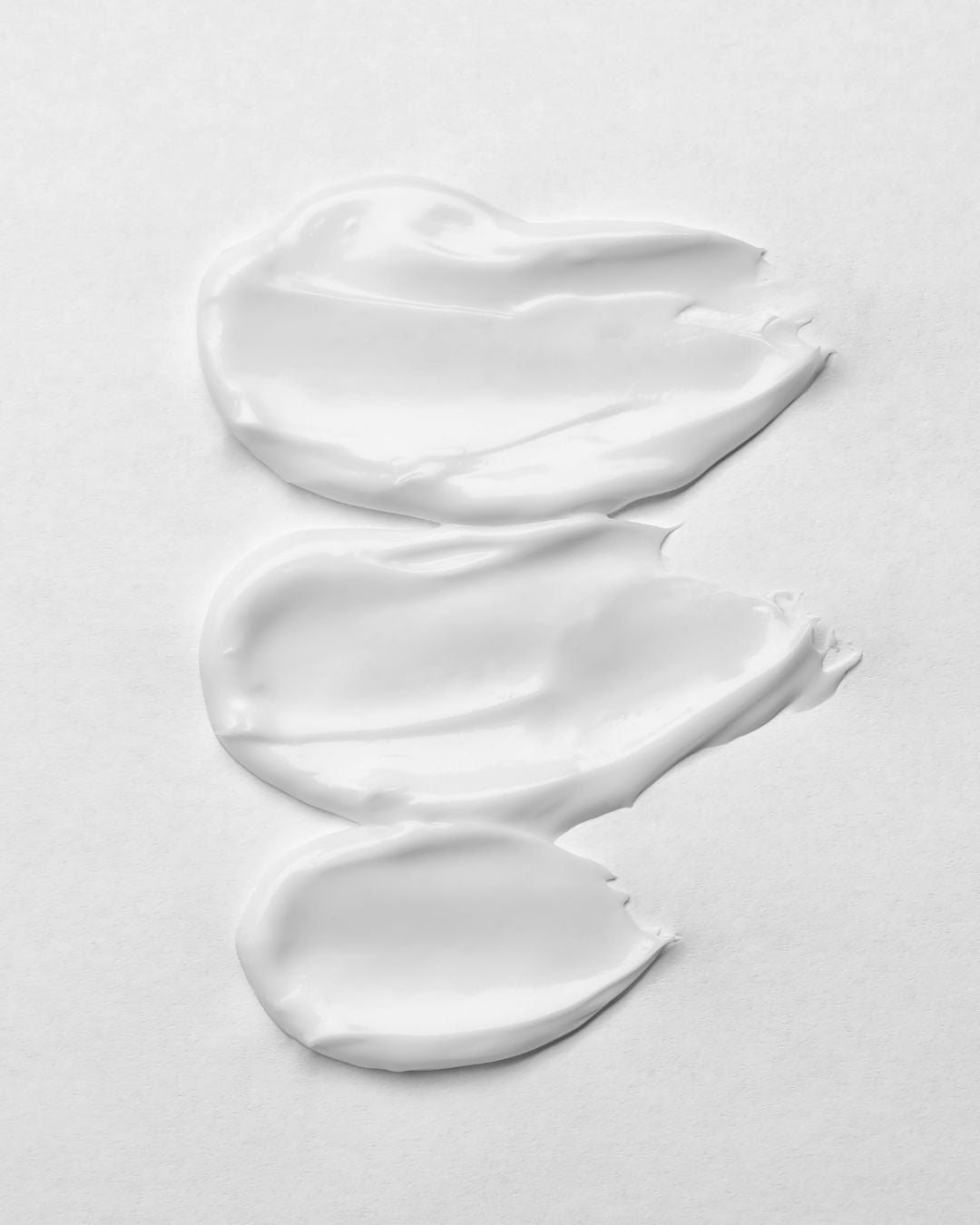 Three smears of the rich, creamy white texture of KALME Cream Cleanser, a moisturising water-free cleanser that cleans without stripping sensitive skin