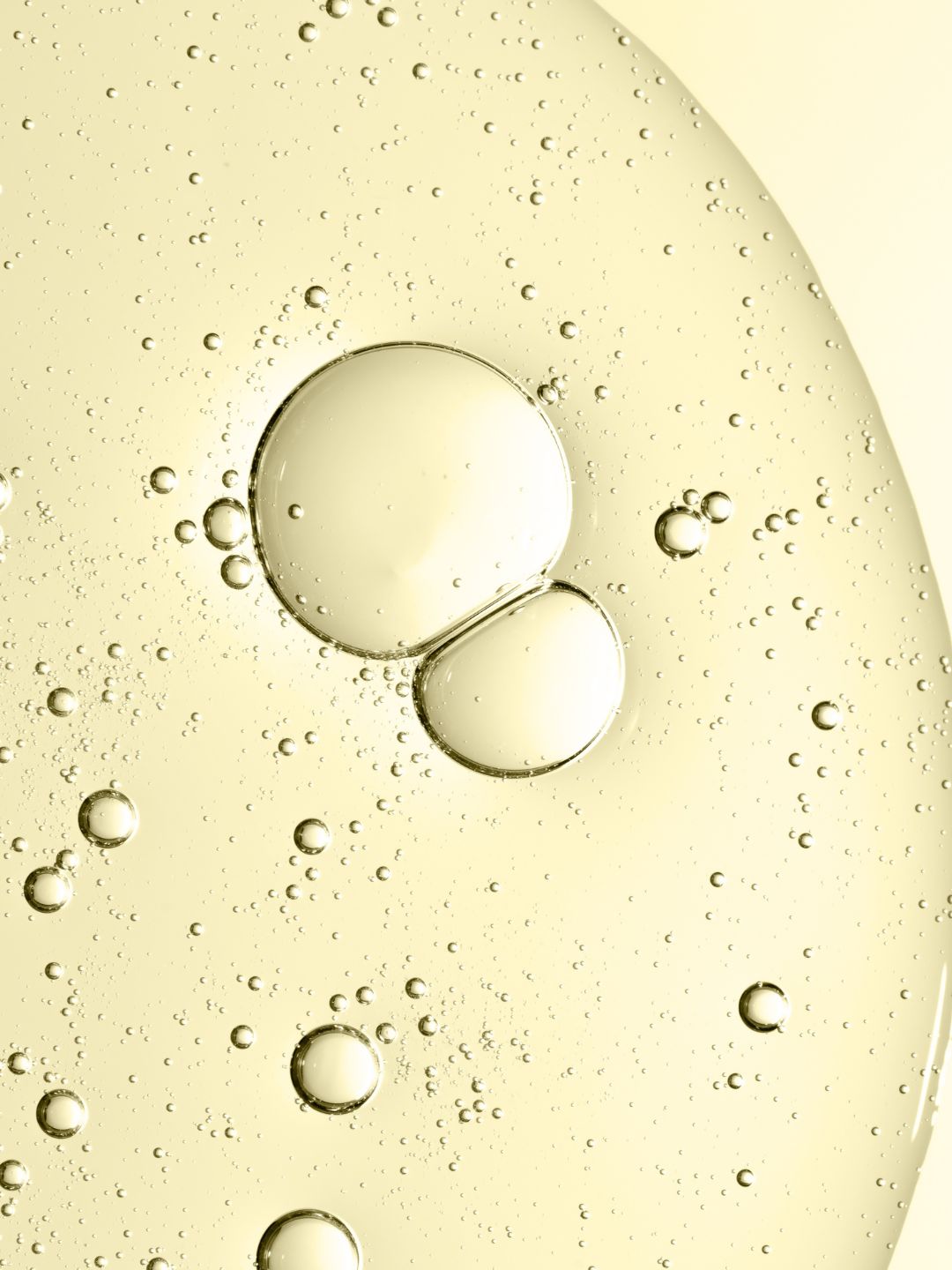 Macro of a pale golden liquid with suspended droplets, representing Acetyl Tetrapeptide-15, the calming desensitising peptide in KALME Undercoat