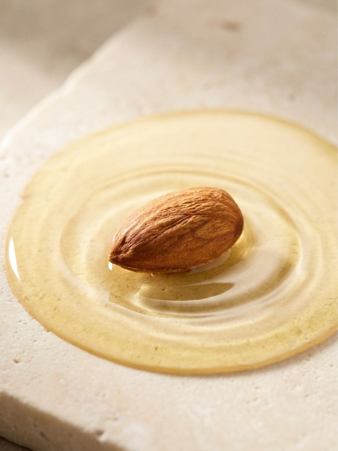 Golden sweet almond oil with a single almond, a soothing plant-based active in KALME's water-free cream cleanser for sensitive, rosacea-prone skin